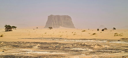 Tassili in lontananza nel deserto con la polvere sollevata dal vento